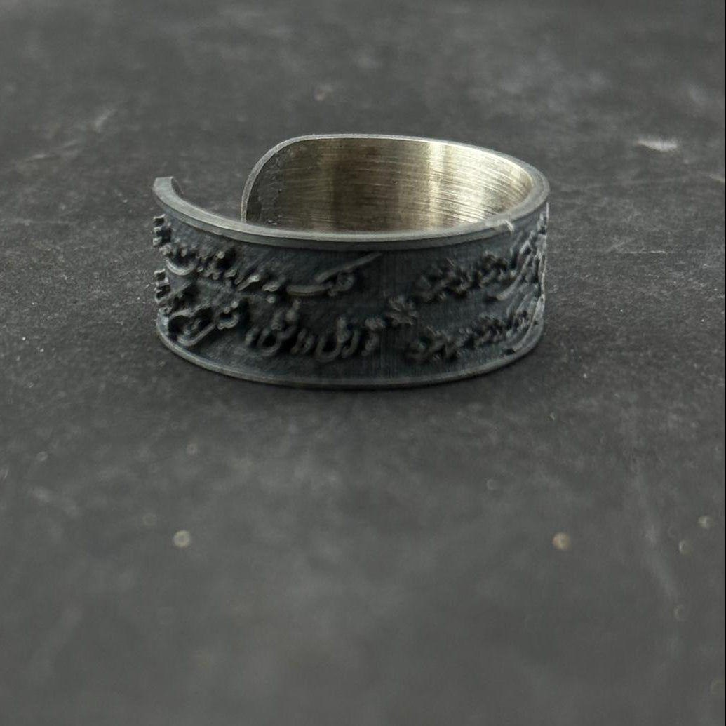 Silver ring with textured design on a dark gray background
